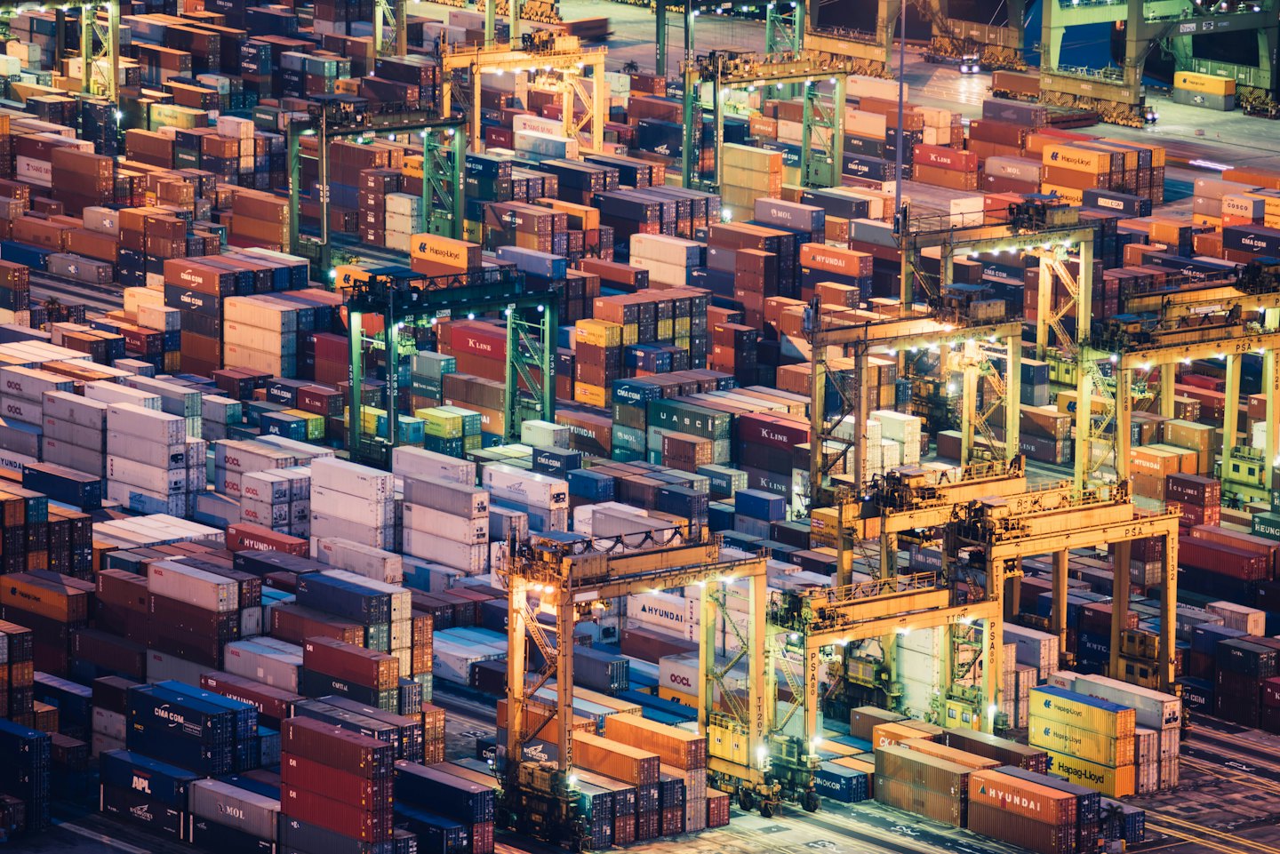Busy shipping port at night with illuminated cargo containers.