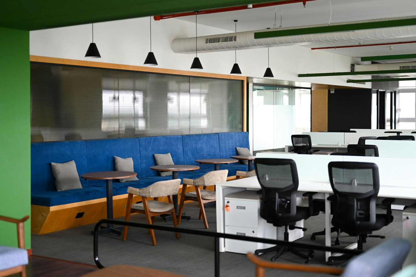 Modern office lounge area with blue bench and workstations.